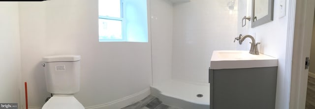 bathroom with vanity, toilet, and a shower