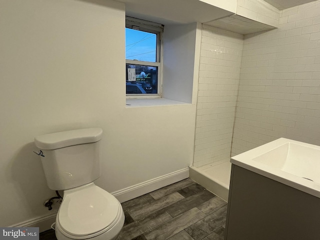 bathroom featuring tiled shower, wood-type flooring, vanity, and toilet