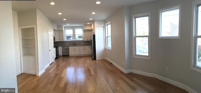 kitchen with white cabinets, appliances with stainless steel finishes, light hardwood / wood-style flooring, and plenty of natural light