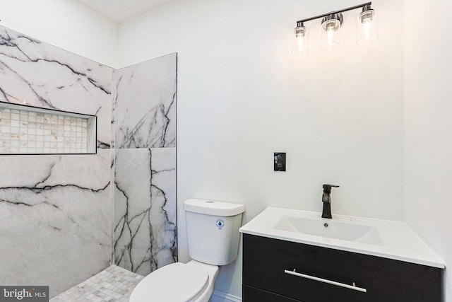 bathroom with tiled shower, vanity, and toilet