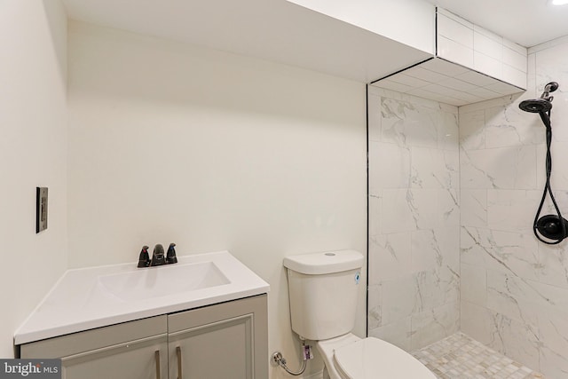 bathroom with tiled shower, vanity, and toilet