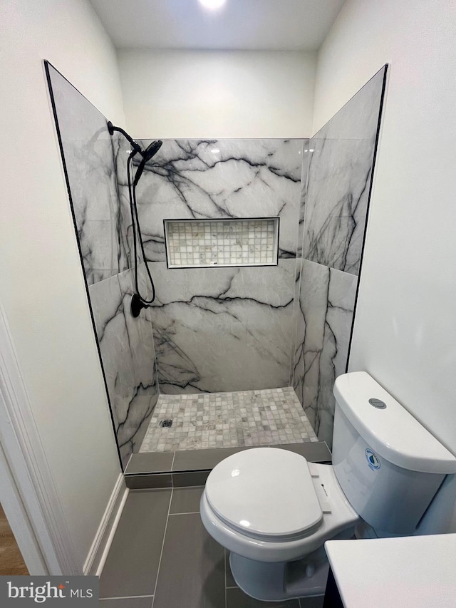 bathroom with a tile shower, tile patterned floors, and toilet