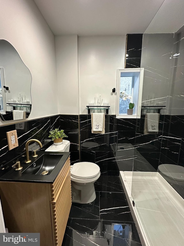 bathroom featuring walk in shower, vanity, tile walls, and toilet