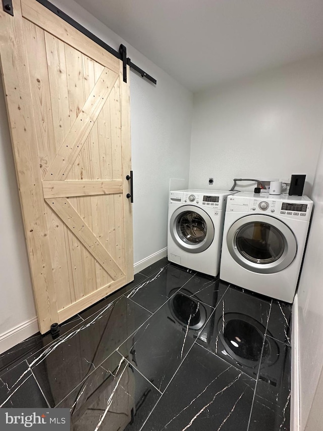 clothes washing area with washer and dryer, a barn door, and dark tile patterned floors