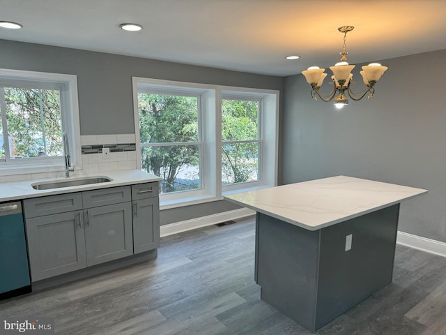 kitchen featuring dark hardwood / wood-style flooring, stainless steel dishwasher, hanging light fixtures, and sink