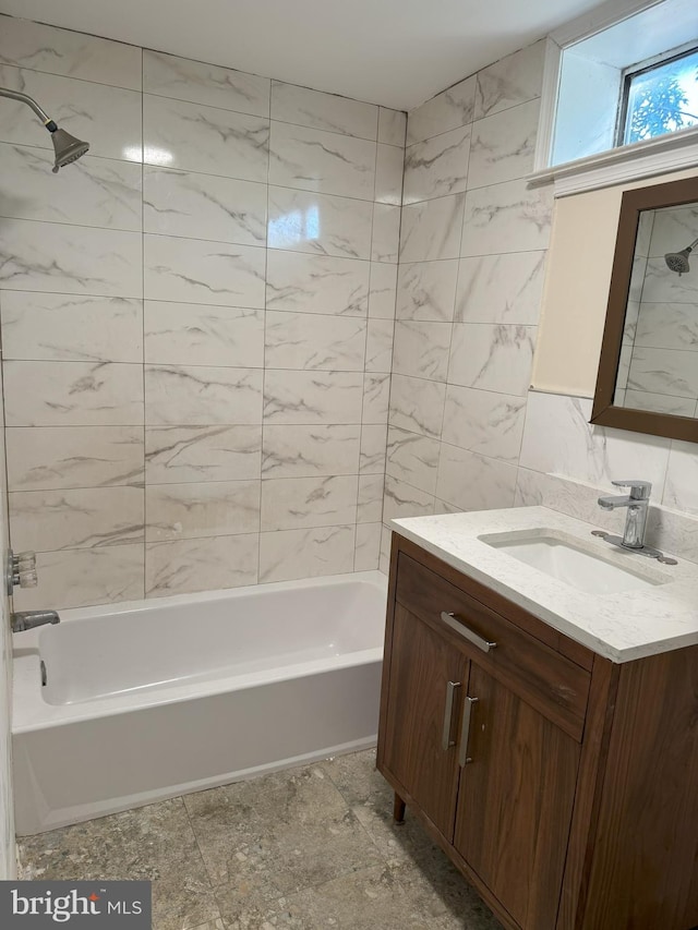 bathroom with vanity, tiled shower / bath, and tile walls