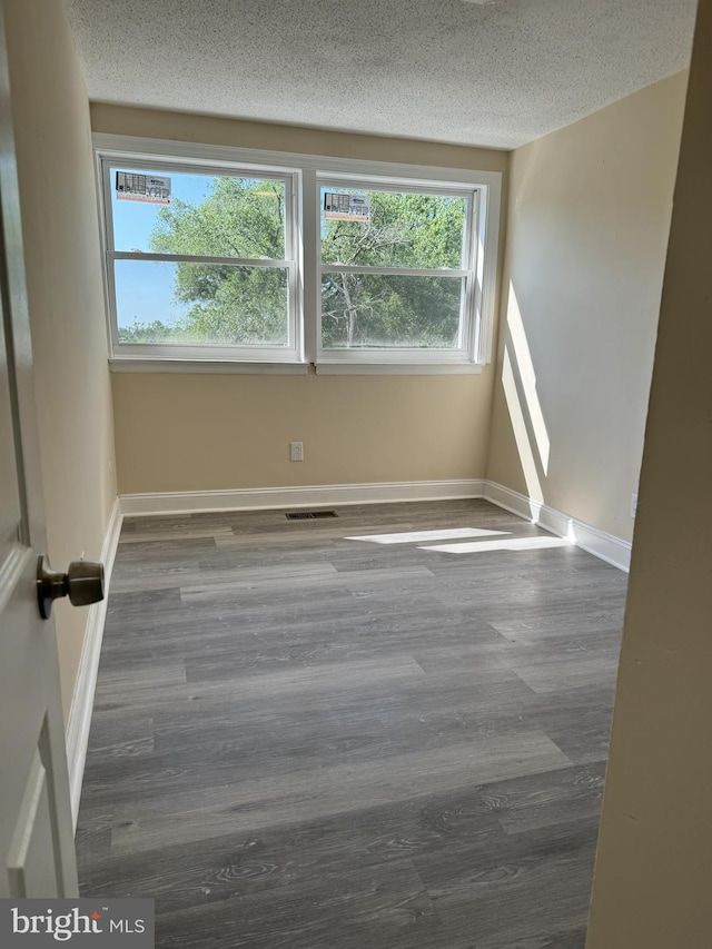 unfurnished room with dark hardwood / wood-style floors and a textured ceiling