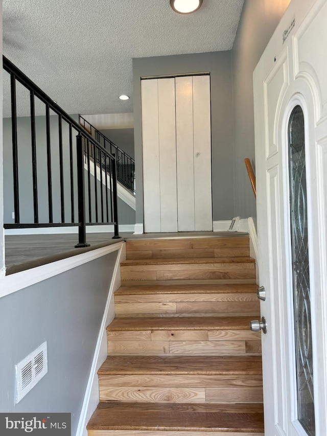 stairs featuring hardwood / wood-style floors and a textured ceiling