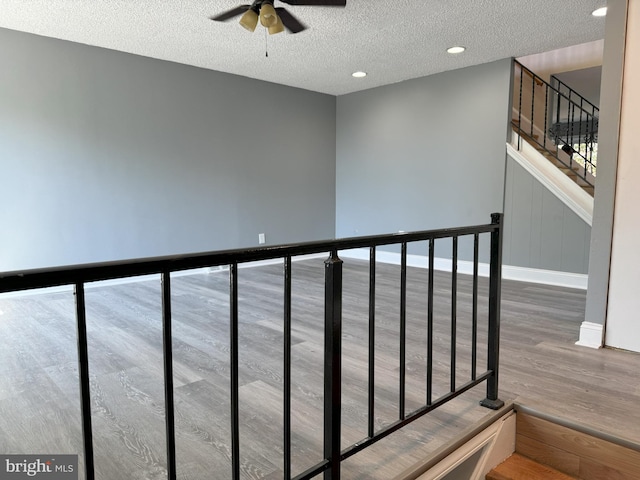 staircase with ceiling fan, a textured ceiling, and hardwood / wood-style flooring