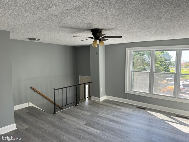 empty room featuring ceiling fan, light wood-type flooring, and a textured ceiling