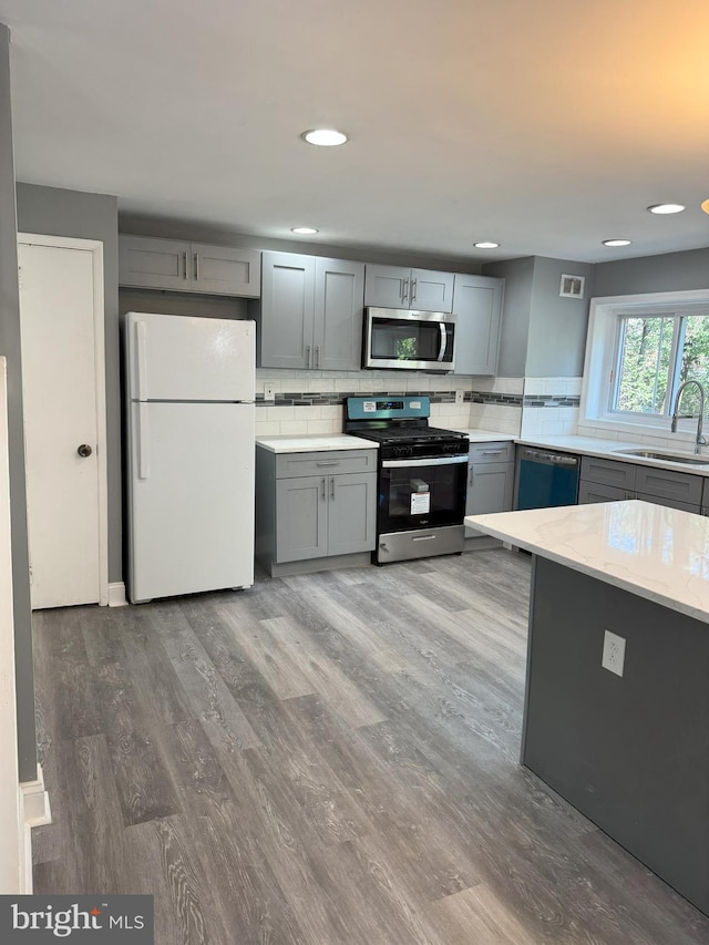 kitchen featuring hardwood / wood-style floors, stainless steel appliances, gray cabinetry, and sink