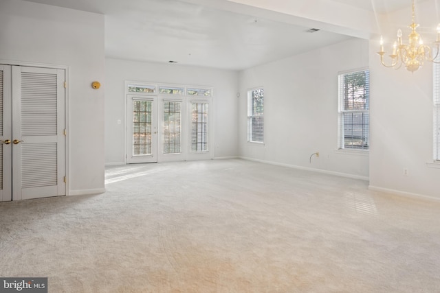 carpeted empty room with a notable chandelier