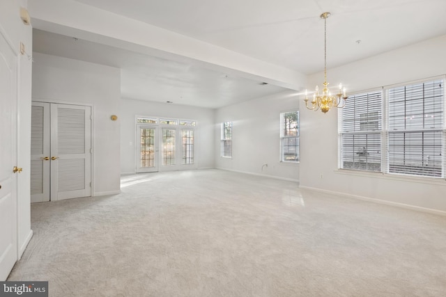 carpeted spare room with beam ceiling and a notable chandelier