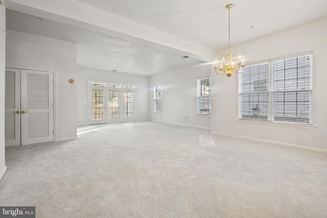 empty room featuring beam ceiling, light colored carpet, and a healthy amount of sunlight