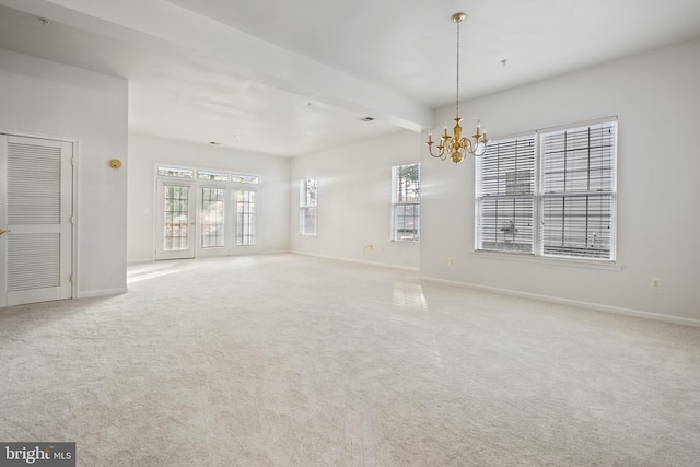 carpeted spare room featuring a notable chandelier and beam ceiling