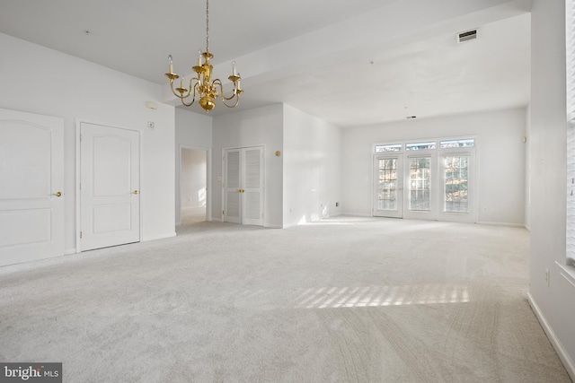 carpeted empty room with a notable chandelier