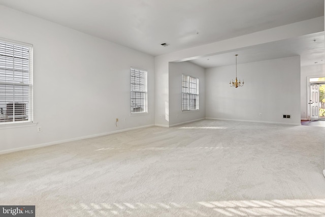 unfurnished room with light carpet and a notable chandelier