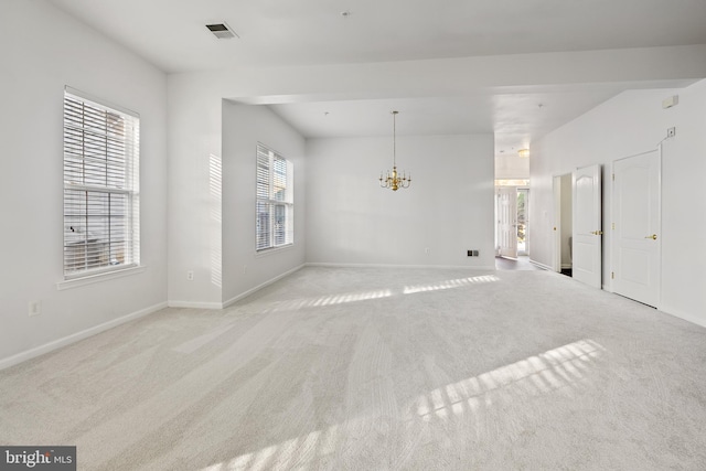 carpeted empty room featuring a chandelier and a healthy amount of sunlight