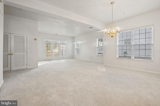 carpeted empty room with beam ceiling, an inviting chandelier, and a wealth of natural light