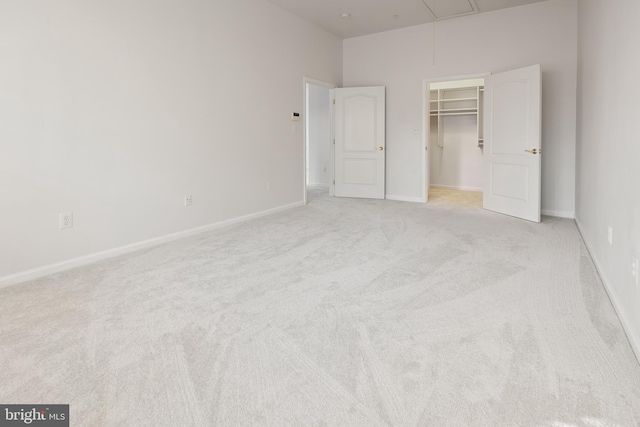 unfurnished bedroom featuring a walk in closet, a closet, and light colored carpet