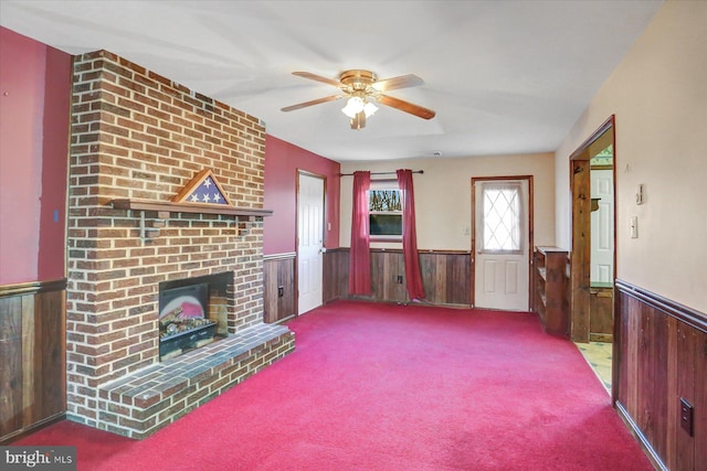 unfurnished living room with ceiling fan, a fireplace, light carpet, and wood walls