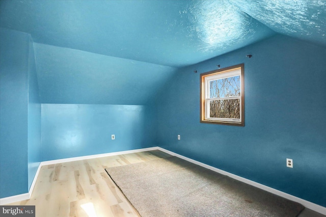 additional living space with wood-type flooring, a textured ceiling, and lofted ceiling