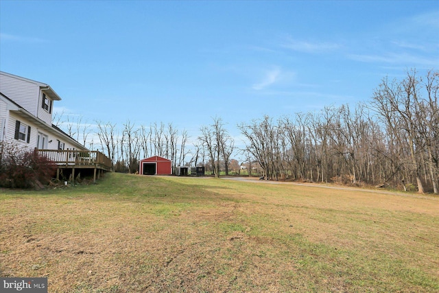 view of yard featuring a wooden deck, an outbuilding, and a garage