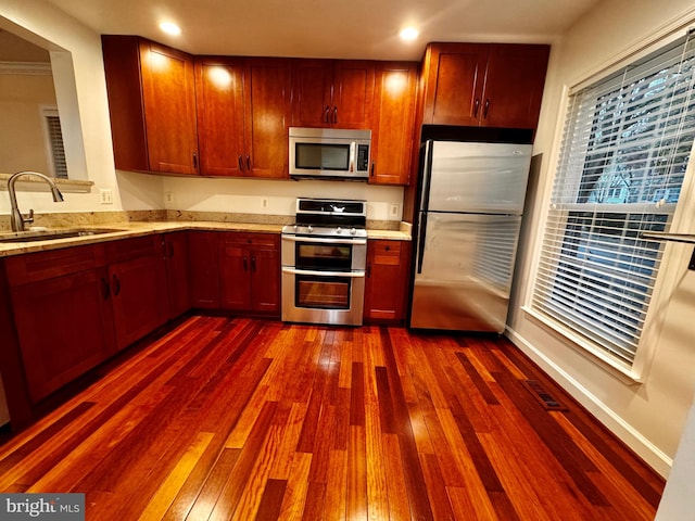 kitchen with dark wood-type flooring, light stone countertops, sink, and stainless steel appliances