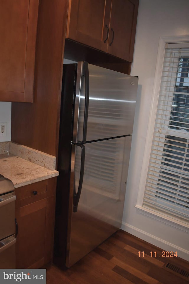 kitchen with electric range, dark hardwood / wood-style floors, light stone counters, and stainless steel refrigerator