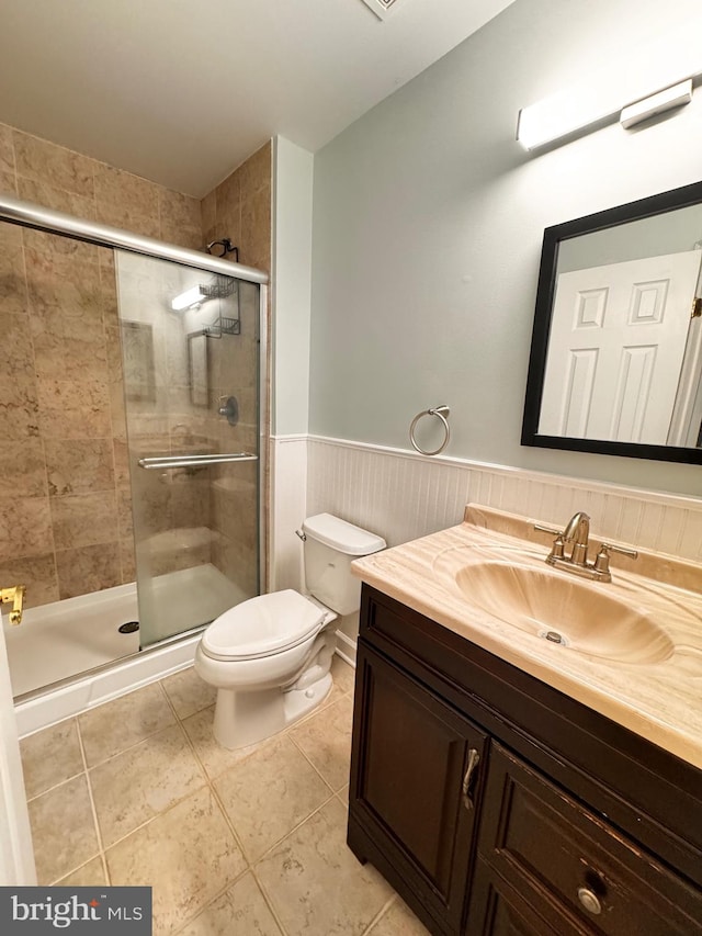 bathroom featuring tile patterned flooring, vanity, toilet, and a shower with shower door