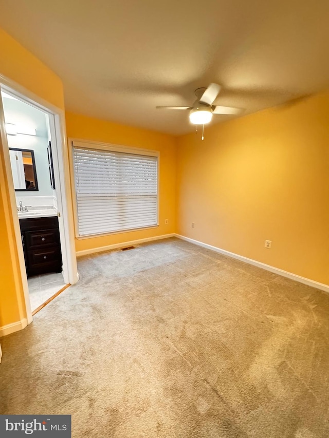 unfurnished bedroom with carpet flooring, ensuite bathroom, and ceiling fan