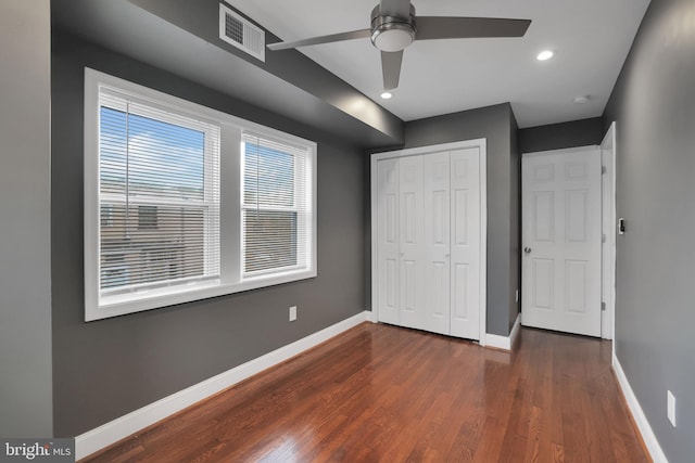 unfurnished bedroom with a closet, dark wood-type flooring, and ceiling fan