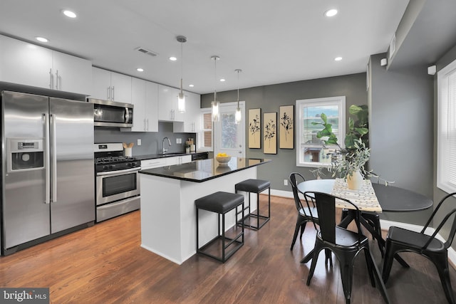 kitchen featuring decorative light fixtures, dark hardwood / wood-style floors, white cabinetry, and stainless steel appliances