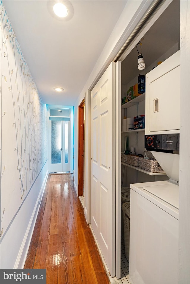 hallway with hardwood / wood-style flooring, french doors, and stacked washer and clothes dryer