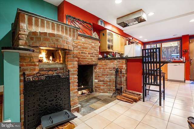 kitchen featuring white appliances, a breakfast bar area, light tile patterned floors, and a brick fireplace