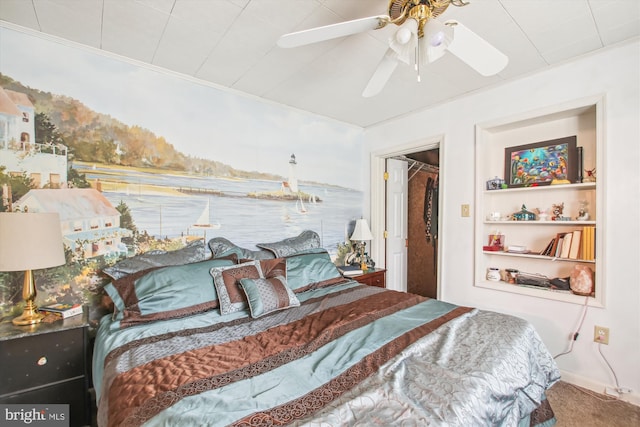 carpeted bedroom featuring ceiling fan, a spacious closet, and crown molding