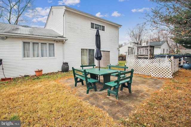 back of property featuring a wooden deck, a patio area, and a lawn