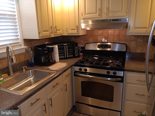 kitchen with gas range, sink, range hood, fridge, and white cabinets