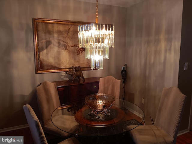 dining space with wood-type flooring and an inviting chandelier