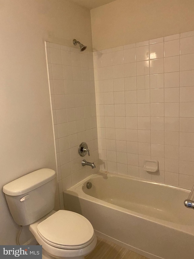 bathroom with tiled shower / bath combo and toilet