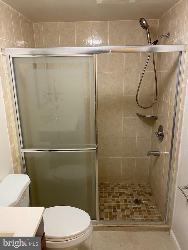 bathroom featuring tile patterned flooring, vanity, toilet, and walk in shower