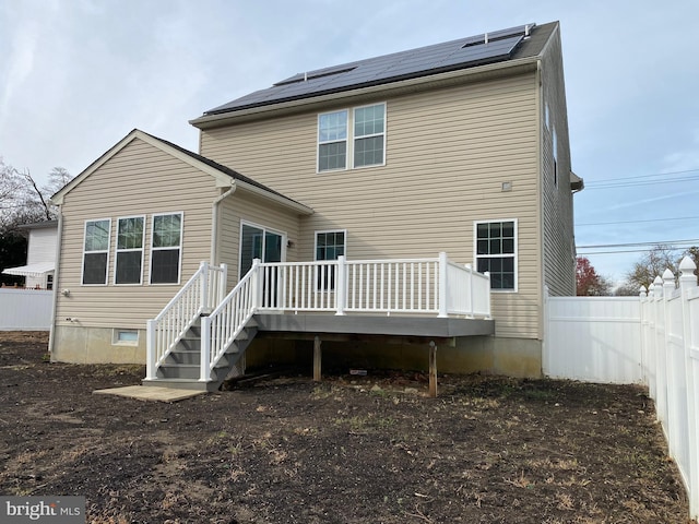 back of house with solar panels and a wooden deck