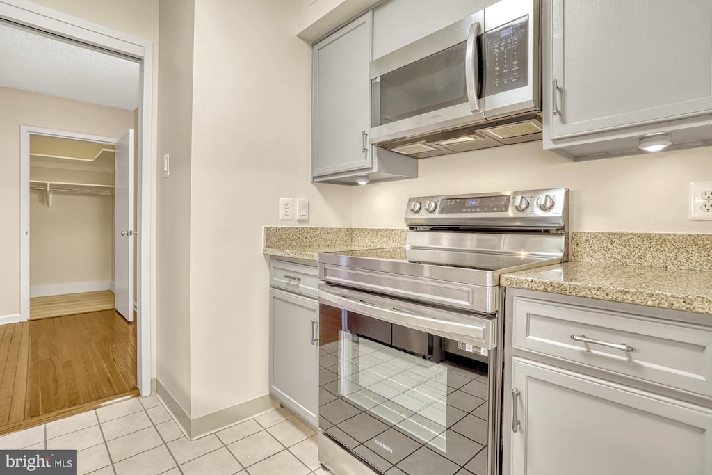 kitchen featuring light stone counters, appliances with stainless steel finishes, and light tile patterned flooring