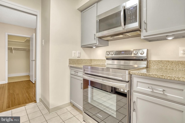 kitchen featuring light stone counters, appliances with stainless steel finishes, and light tile patterned flooring