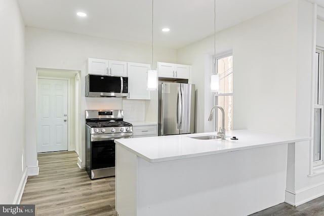 kitchen featuring white cabinets, sink, decorative light fixtures, kitchen peninsula, and stainless steel appliances