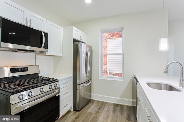 kitchen featuring sink, white cabinets, light hardwood / wood-style flooring, and appliances with stainless steel finishes