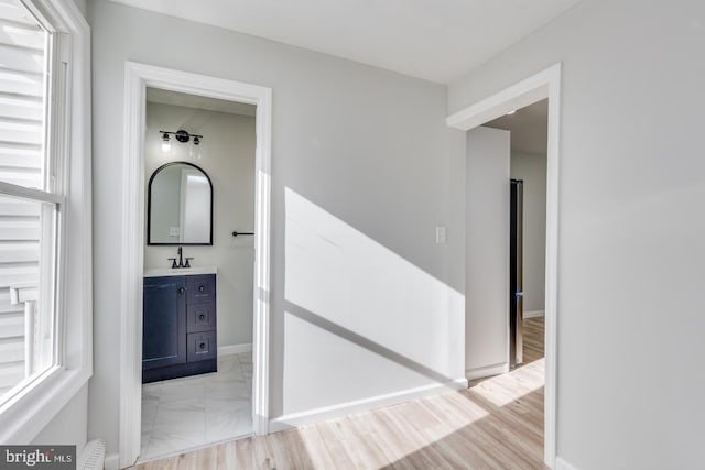 corridor with sink and light hardwood / wood-style flooring