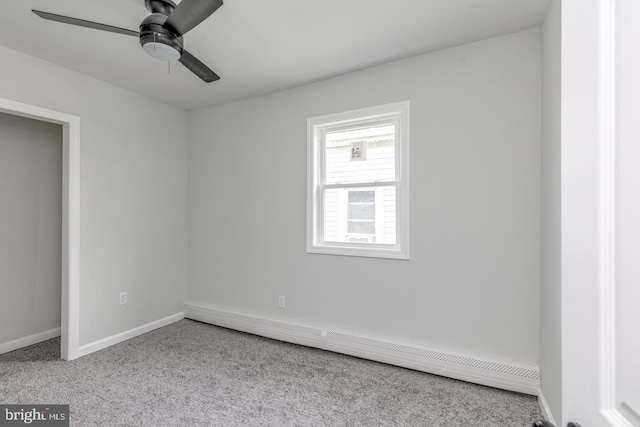 carpeted empty room featuring ceiling fan and a baseboard heating unit