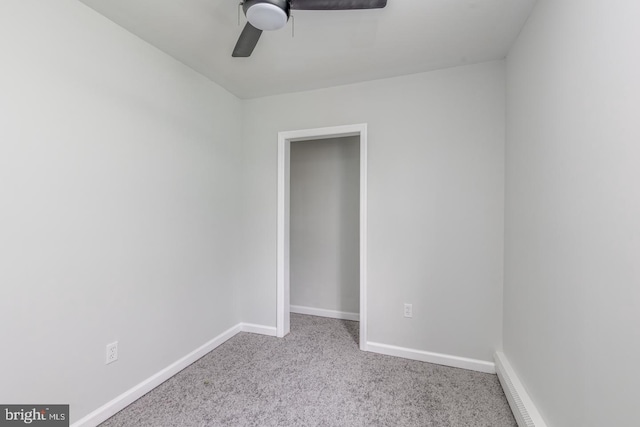 carpeted empty room featuring ceiling fan and a baseboard heating unit