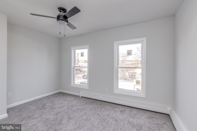 carpeted empty room featuring a wealth of natural light, a baseboard heating unit, and ceiling fan